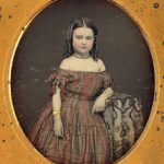Girl in off-shoulder plaid dress, 1850s
